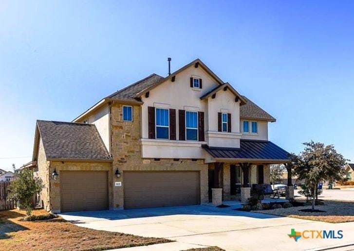 view of front of house with a porch, a standing seam roof, stone siding, concrete driveway, and an attached garage