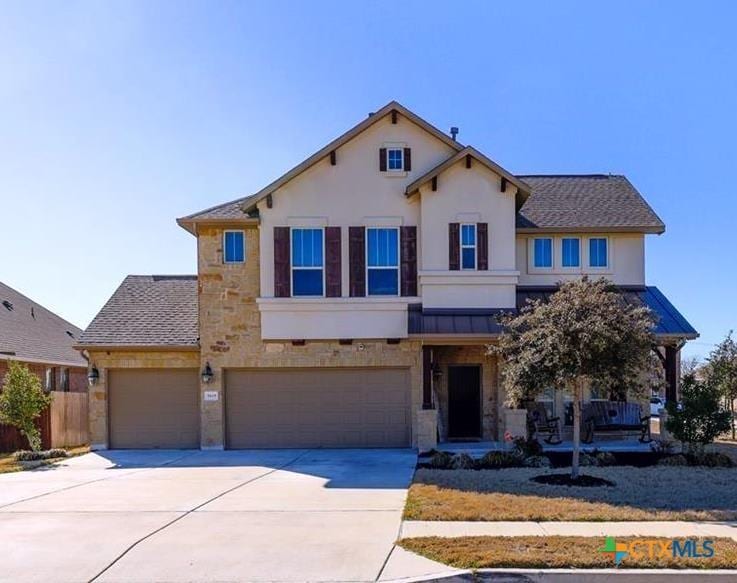 view of front of house featuring fence, concrete driveway, stone siding, stucco siding, and a porch