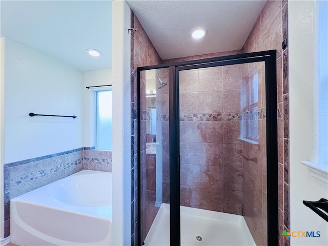 bathroom with tile walls and shower with separate bathtub