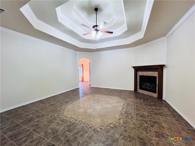 unfurnished living room with a fireplace, a tray ceiling, ceiling fan, and crown molding