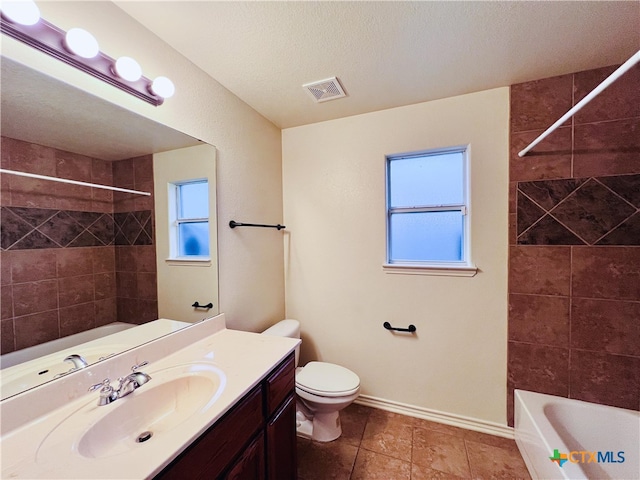 full bathroom with vanity, a textured ceiling, tiled shower / bath combo, tile patterned flooring, and toilet