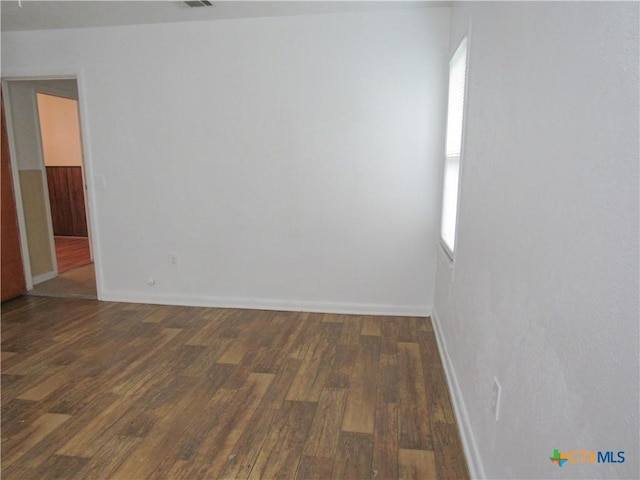 spare room with baseboards, wood finished floors, and visible vents