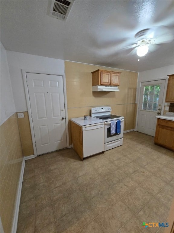 kitchen featuring visible vents, brown cabinetry, white appliances, ceiling fan, and under cabinet range hood