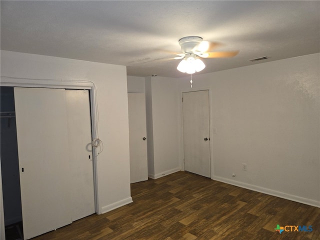 unfurnished bedroom featuring ceiling fan, baseboards, visible vents, dark wood-style floors, and a closet