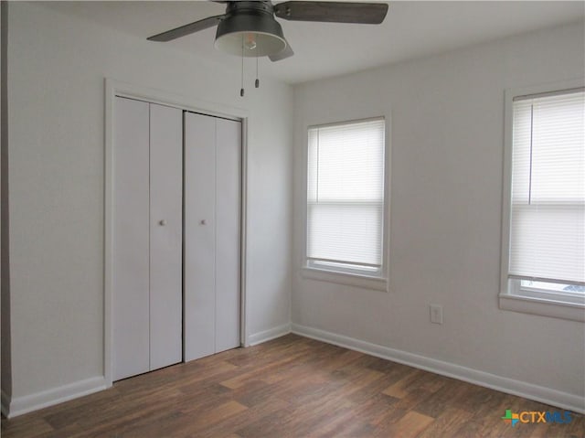 unfurnished bedroom featuring baseboards, a ceiling fan, a closet, and wood finished floors