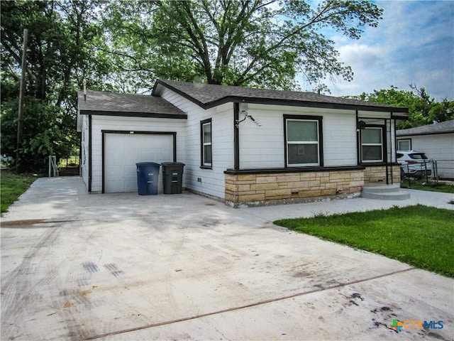 ranch-style home with a garage, roof with shingles, stone siding, and concrete driveway