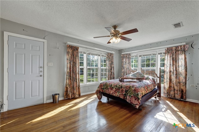 bedroom with a textured ceiling, hardwood / wood-style flooring, and ceiling fan