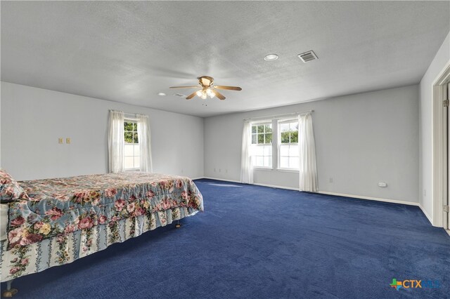 unfurnished bedroom featuring a textured ceiling, multiple windows, and ceiling fan