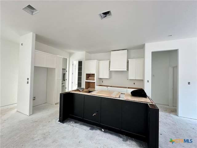 kitchen with white cabinetry, a large island, and premium range hood