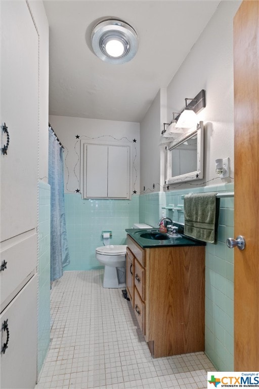 bathroom with tile patterned floors, vanity, toilet, and tile walls