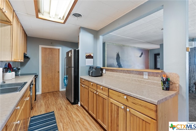 kitchen featuring light wood-type flooring, sink, and stainless steel refrigerator