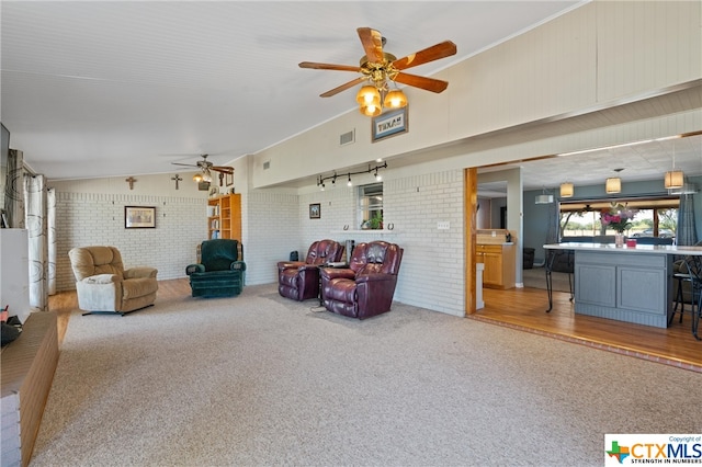 living room with wood-type flooring, ceiling fan, and brick wall