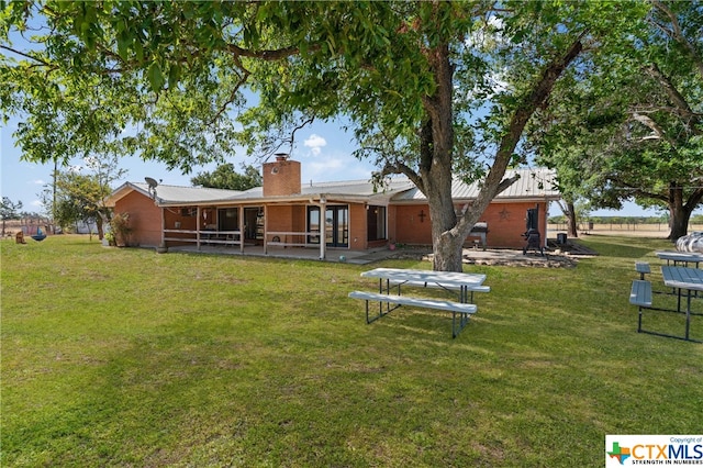 rear view of house with a lawn and a patio