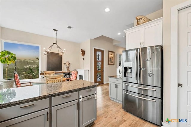 kitchen with light stone countertops, gray cabinets, light wood-type flooring, stainless steel refrigerator with ice dispenser, and recessed lighting