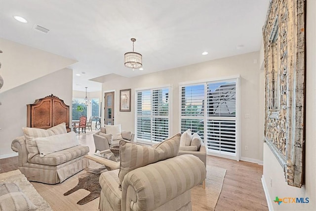 living area with visible vents, baseboards, light wood-style floors, a notable chandelier, and recessed lighting