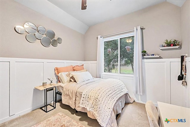 bedroom featuring lofted ceiling, a wainscoted wall, and carpet flooring