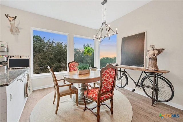 dining area featuring light wood-style floors, baseboards, and an inviting chandelier