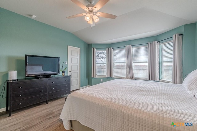 bedroom with baseboards, multiple windows, wood finished floors, and vaulted ceiling