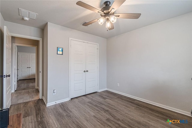 unfurnished bedroom with visible vents, dark wood finished floors, a closet, baseboards, and ceiling fan