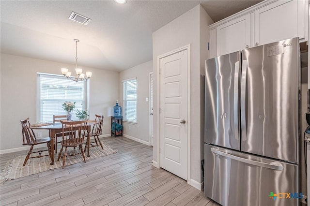 dining space featuring light wood-type flooring, visible vents, baseboards, and a notable chandelier