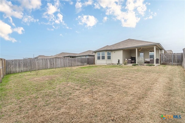 rear view of house featuring a lawn, a patio, and a fenced backyard