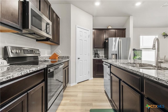 kitchen featuring light hardwood / wood-style floors, sink, dark brown cabinetry, stainless steel appliances, and light stone counters