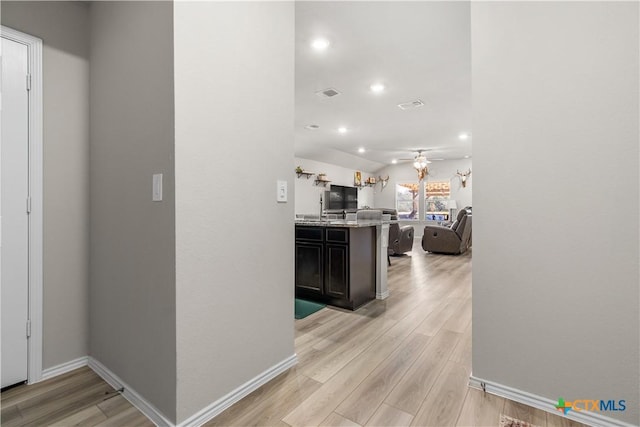 corridor with light hardwood / wood-style floors and vaulted ceiling