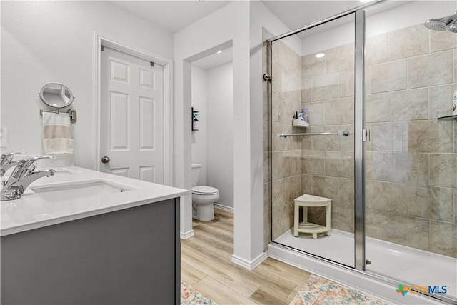 bathroom featuring hardwood / wood-style floors, toilet, walk in shower, and vanity