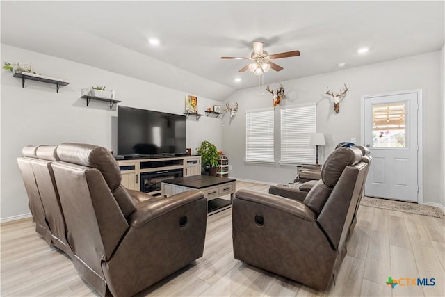 living room featuring ceiling fan, light hardwood / wood-style floors, and vaulted ceiling