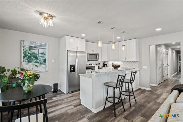 458 Seele St, New Braunfels, TX 78130 - kitchen featuring appliances with stainless steel finishes, dark wood-type flooring, white cabinetry, a breakfast bar area, and recessed lighting