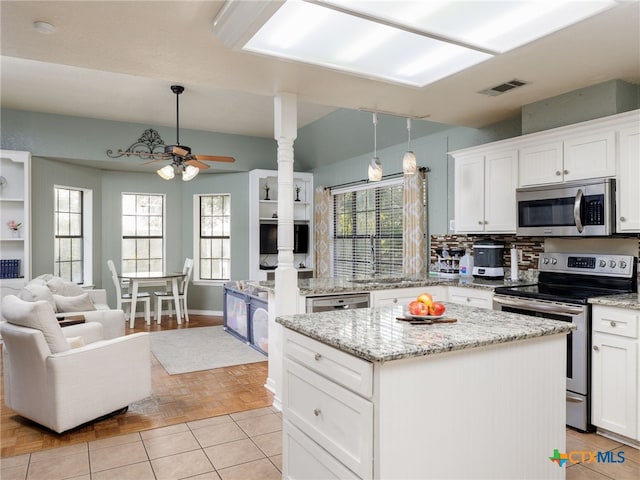 kitchen featuring stainless steel appliances, open floor plan, white cabinetry, a kitchen island, and a sink