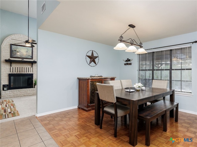 dining room featuring a fireplace, light tile patterned floors, visible vents, ceiling fan, and baseboards