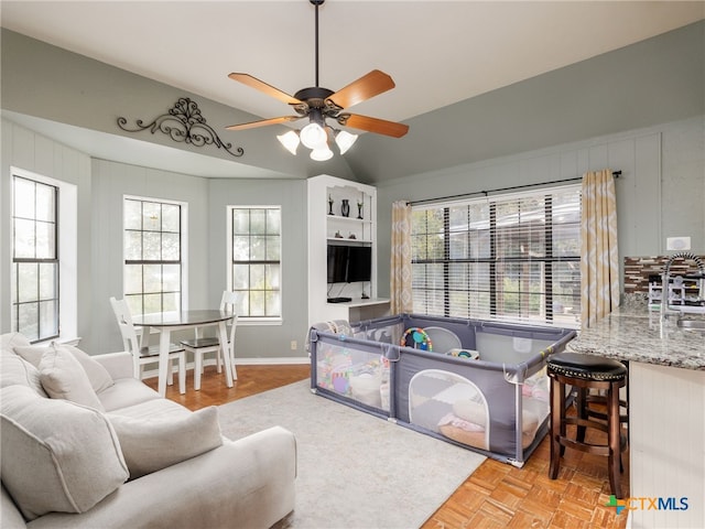 game room with a ceiling fan, lofted ceiling, and baseboards