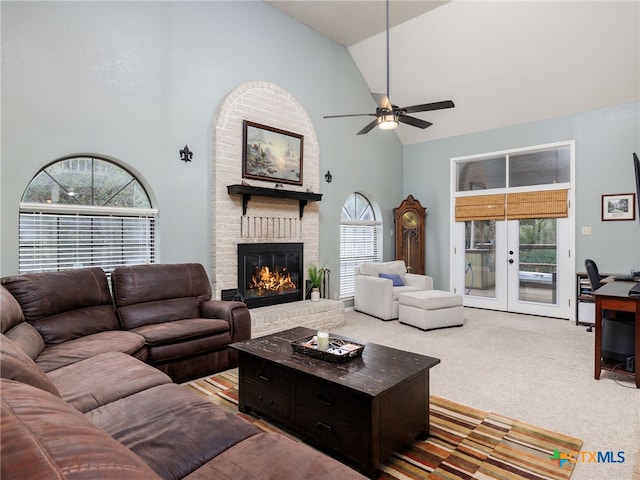 carpeted living area with a fireplace, high vaulted ceiling, a wealth of natural light, and french doors