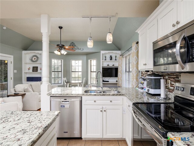 kitchen with lofted ceiling, open floor plan, a peninsula, stainless steel appliances, and a sink