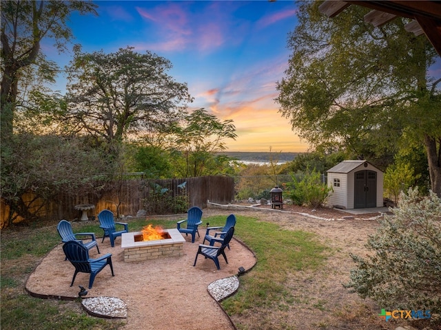 view of yard with a fire pit, a fenced backyard, an outbuilding, a storage unit, and a patio area