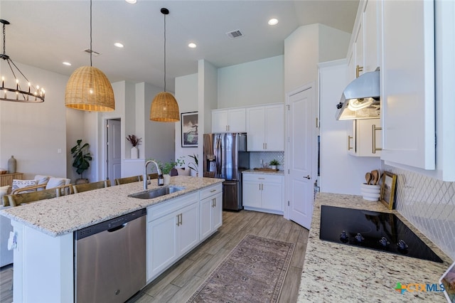 kitchen featuring stainless steel appliances, decorative light fixtures, sink, an island with sink, and white cabinets