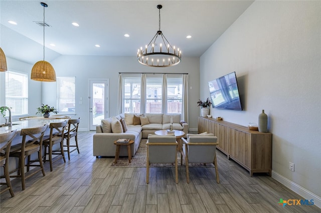 living room featuring hardwood / wood-style floors, a chandelier, and vaulted ceiling