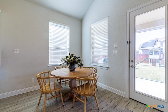 dining space with a wealth of natural light, lofted ceiling, and light hardwood / wood-style flooring