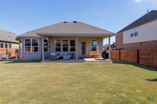 back of house with a patio, an outdoor living space, and a yard