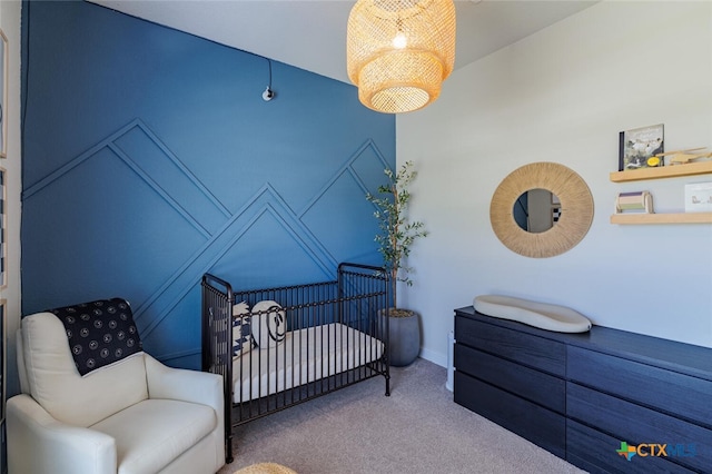 carpeted bedroom featuring an inviting chandelier and a nursery area