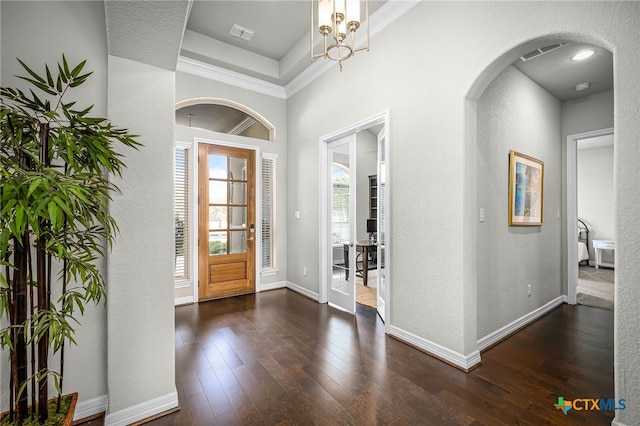 foyer with hardwood / wood-style flooring, baseboards, visible vents, and arched walkways