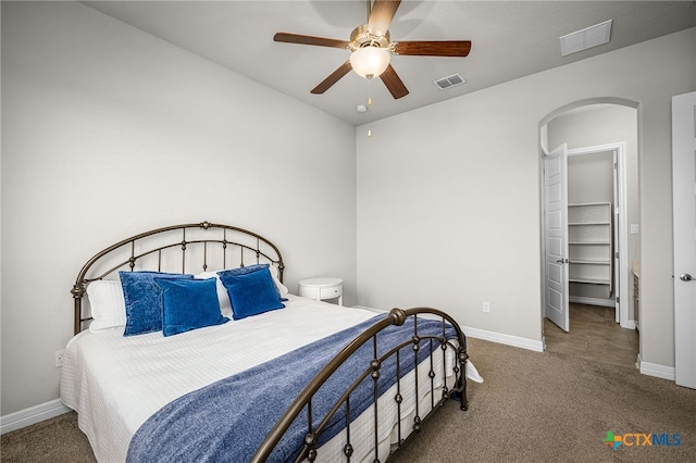 carpeted bedroom featuring visible vents, arched walkways, baseboards, and a spacious closet