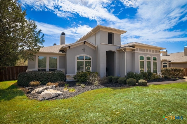 mediterranean / spanish-style house featuring stucco siding, a chimney, a front lawn, and fence