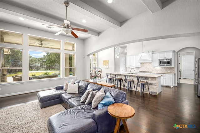 living area featuring dark wood finished floors, beamed ceiling, recessed lighting, and arched walkways