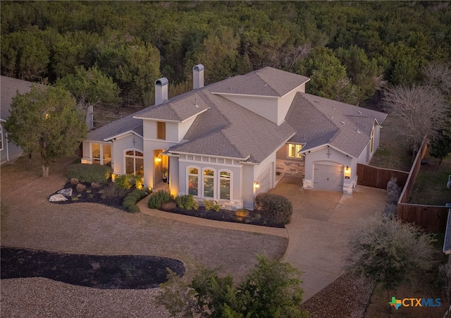 view of front of home with driveway, a forest view, a garage, and fence