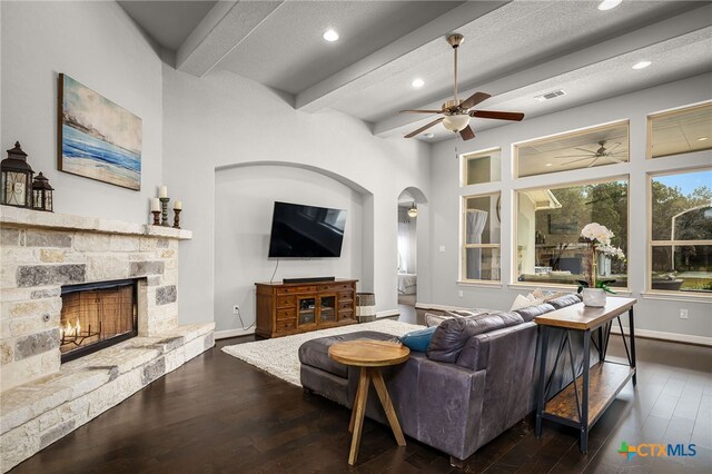 living area with wood finished floors, visible vents, a fireplace, arched walkways, and beamed ceiling