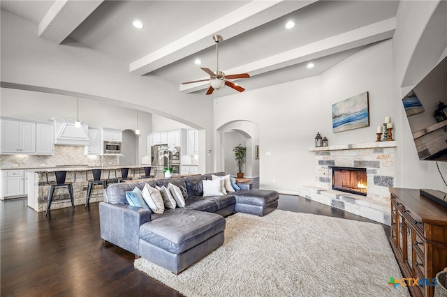 living room with beam ceiling, a fireplace, ceiling fan, and dark wood-style flooring