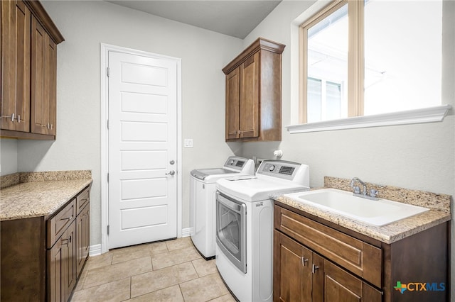 clothes washing area featuring light tile patterned floors, cabinet space, washer and dryer, and a sink