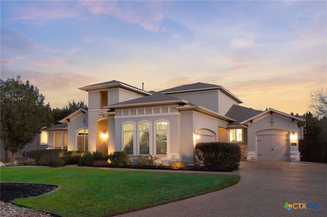 mediterranean / spanish home with a garage, stucco siding, driveway, and a front lawn